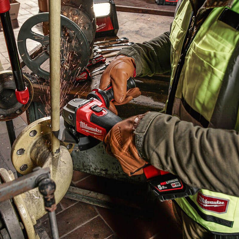 Worker using the MILWAUKEE® M18 FUEL™ Cordless Angle Grinder to cut metal, highlighting its cordless design, powerful brushless motor, and ergonomic handle for precision and comfort on demanding jobsite tasks. Worker using the MILWAUKEE® M18 FUEL™ Cordless Angle Grinder to cut metal, highlighting its cordless design, powerful brushless motor, and ergonomic handle for precision and comfort on demanding jobsite tasks.